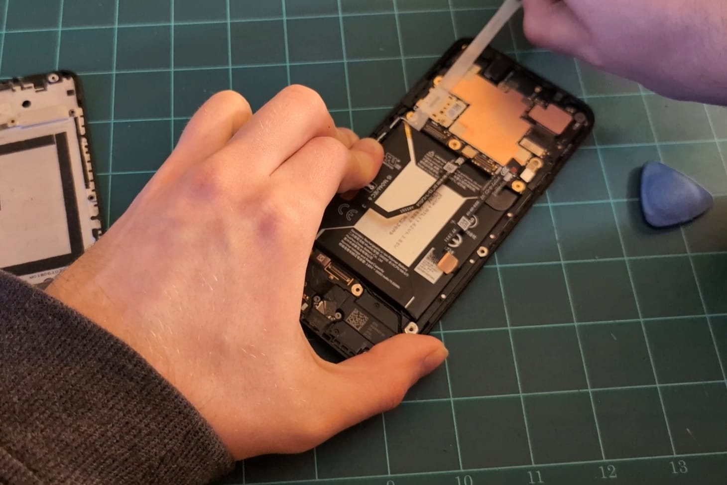 Pulling the stretch-release strip to remove the battery