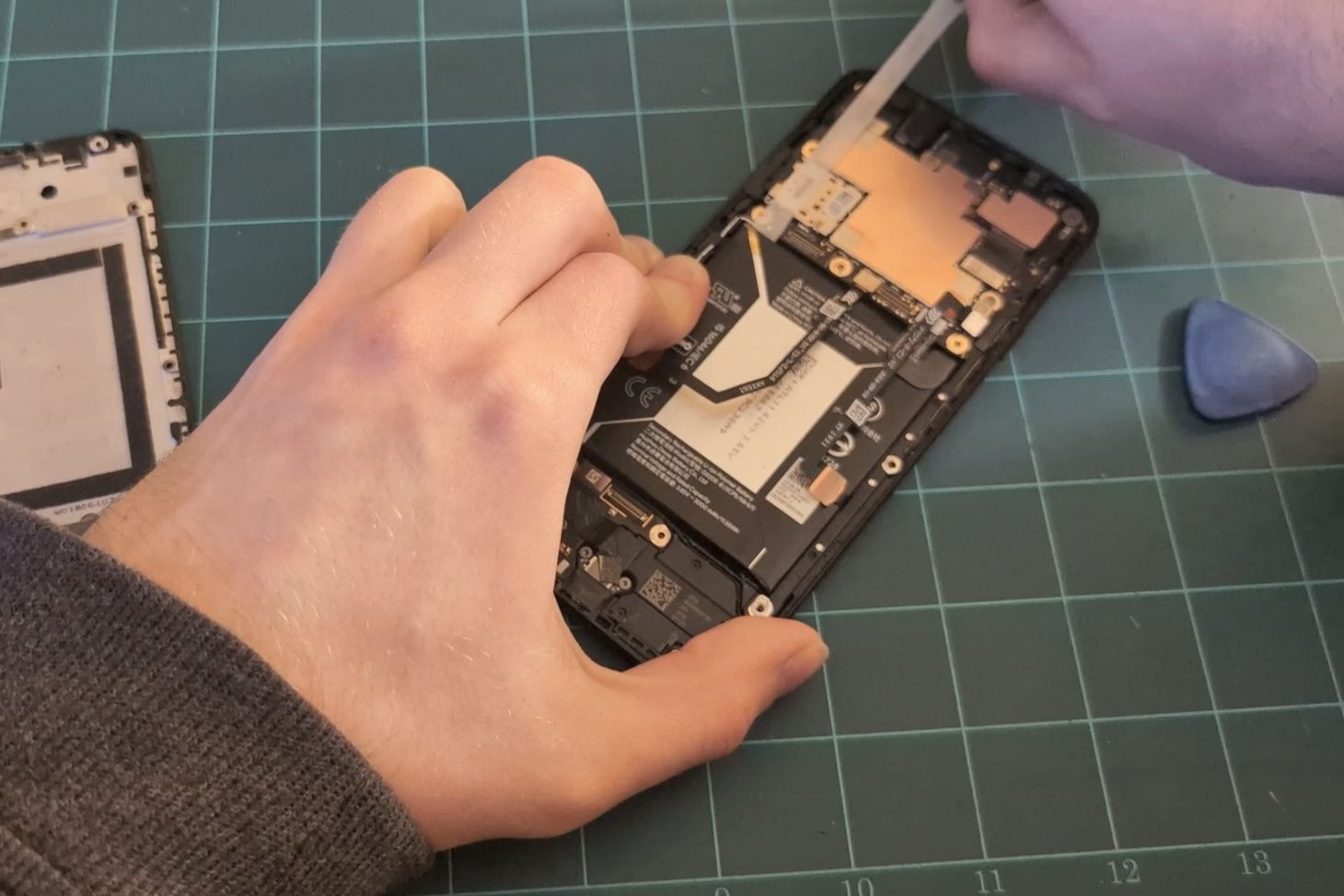Pulling the stretch-release strip to remove the battery.
